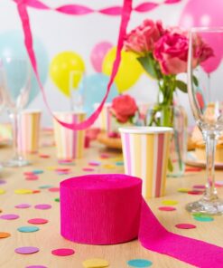 Hot pink crepepapir rulle på pyntet festbord med konfetti, balloner, blomster og festpynt
