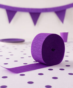 Mørklilla crepepapir på hvidt bord med lilla konfetti og vimpelguirlande – festligt dekorationsbillede.