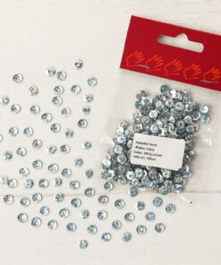 Pose med 6 mm sølv perlemor-palietter og spredte palietter på en lys træoverflade.