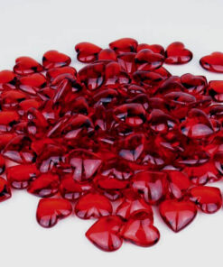 Romantisk bordopdækning med røde roser, bestik og rubinrøde hjerteformede pynte diamanter på hvidt bord.