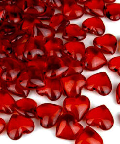 Romantisk bordopdækning med røde roser, bestik og rubinrøde hjerteformede pynte diamanter på hvidt bord.