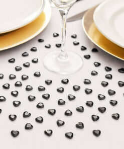 Sorte hjerteformede pynte diamanter i en klar pose med tre større facetterede sorte hjerter vist foran.