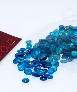 Blå og lilla 6mm palietter spredt ud foran en åben pose på en lys baggrund