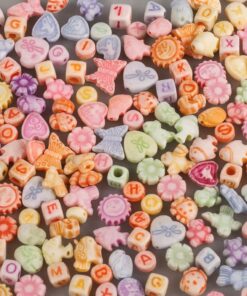 Farverige plastikperler i pastelnuancer med bogstaver og figurer til smykkefremstilling.