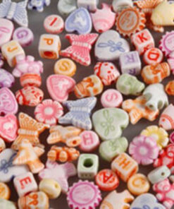 Farverige plastikperler i pastelnuancer med bogstaver og figurer til smykkefremstilling.