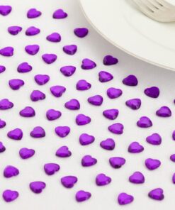 Festligt bord pyntet med lilla hjerte-diamanter, champagneglas og tændte lys omkring en pakke Décor Diamanté pyntesten.