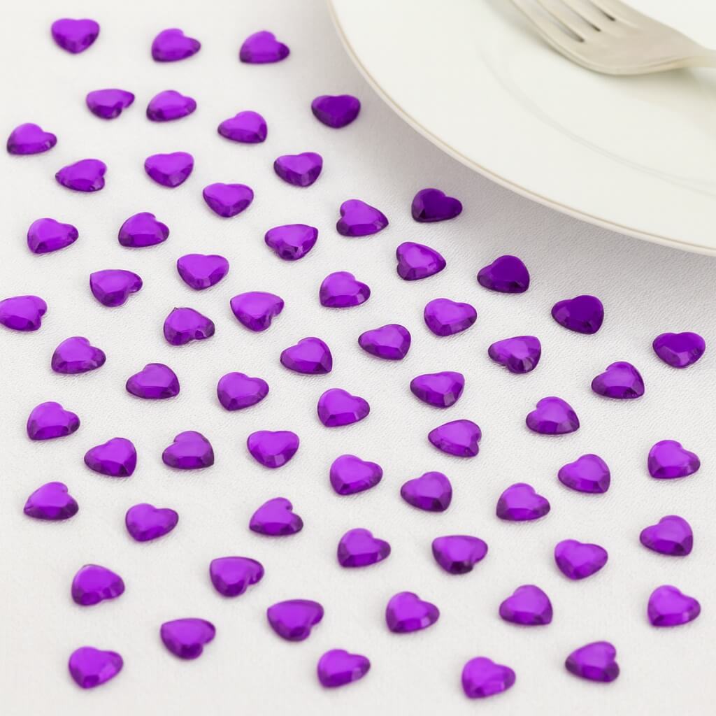 Festligt bord pyntet med lilla hjerte-diamanter, champagneglas og tændte lys omkring en pakke Décor Diamanté pyntesten.