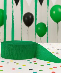 Rulle grønt crepepapir på bord med konfetti, med balloner og streamers i baggrunden.