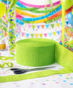 Rulle med limegrønt crepepapir på et festligt bord med konfetti, saks og farverig pynt i baggrunden.