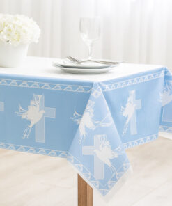 Lyseblå dug med hvide due- og korsmotiver lagt på et bord til barnedåb.