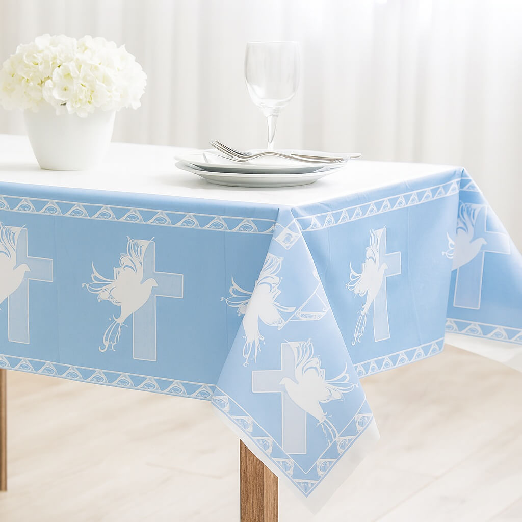 Lyseblå dug med hvide due- og korsmotiver lagt på et bord til barnedåb.