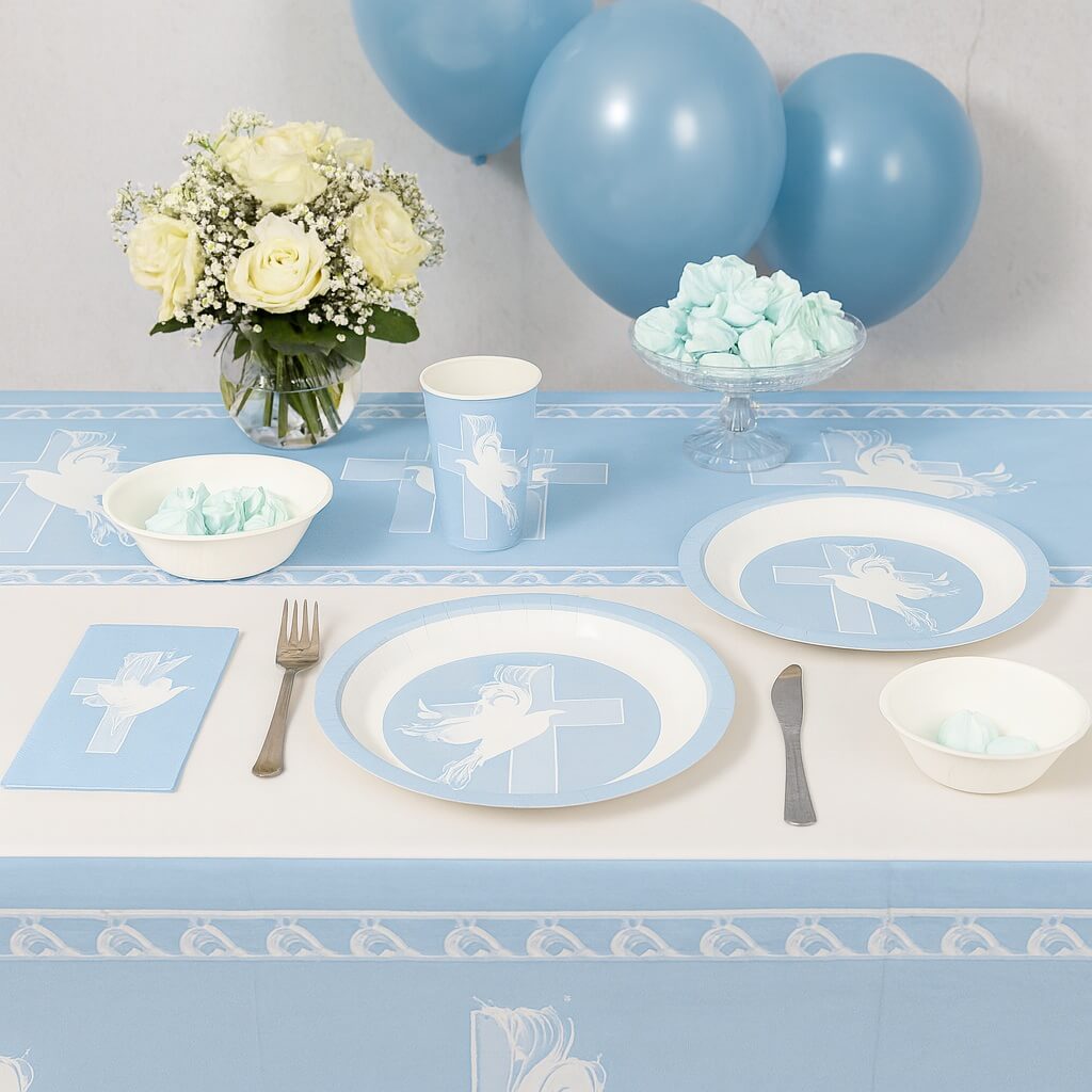 Lyseblå dug med hvide due- og korsmotiver lagt på et bord til barnedåb.
