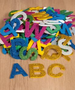 Farverige glitter mosgummi bogstaver spredt ud på træbord med A, B og C i forgrunden