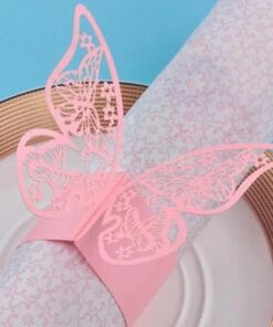 Lyserødt udskåret sommerfugle-servietbånd på dekorativ serviet og tallerken.