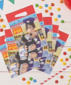 Postmand Per slikposer spredt ud på et bord omgivet af farvede chokoladeknapper og festpynt.