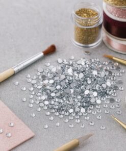 Klare 6mm rhinsten omgivet af hobbytilbehør i et kreativt DIY-miljø.