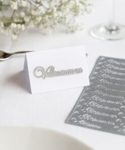 Bordkort med sølv ‘Velkommen’-sticker og ark med stickers på dækket bord.