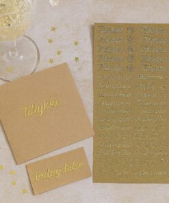 Stemningsbillede med guldstickers, kort og invitation på et lyst bord med stjerner og champagneglas.