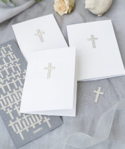 Hvide kort dekoreret med sølvkors-stickers omgivet af stickerark, bånd og dekorationer.