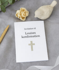 Konfirmationsinvitation med sølv kors-sticker omgivet af blomst, eukalyptus og dekorationer.