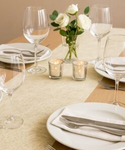 Cremehvid bordløber i webstruktur på pyntet festbord med tallerkener, glas, lys og blomster.