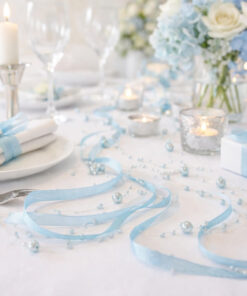 Nærbillede af festbord pyntet med lyseblå satinbånd med perler og stearinlys.