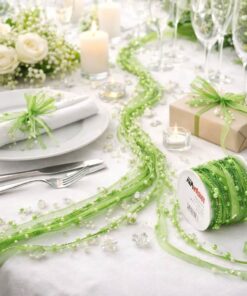 Grønt satinbånd med perler på rulle brugt som bordpynt på elegant festbord med lys, blomster og opdækning