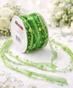 Grønt satinbånd med perler på rulle, delvist udrullet på lyst underlag med dekorativ baggrund