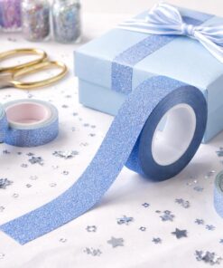 Blå glitter tape brugt til gaveindpakning på lyseblå gaveæske med dekorative hobbyelementer.