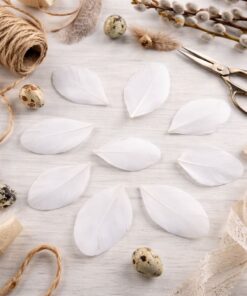 Skårede hvide fjer til DIY pynt på hobbybord med snor, saks og naturmaterialer