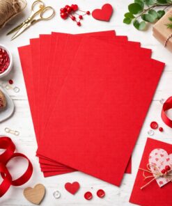 Rød struktureret A4 karton 215 g/m² brugt til håndlavet kortdesign omgivet af hobby materialer på lyst bord