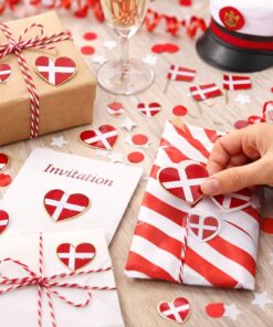 Hånd sætter hjerteformet Dannebrog sticker på gave med rød hvid indpakning til studenterfest og invitation