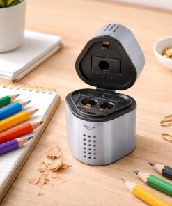 Faber-Castell Grip 2001 trio blyantspidser i sølv i brug på skrivebord med farveblyanter og spåner