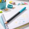 Faber-Castell Jumbo Grip blyant i sort og turkis placeret på notesbog med børnetegning