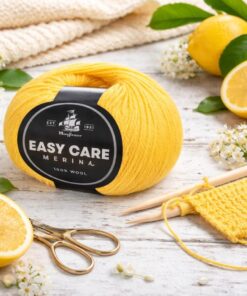 Mayflower Easy Care Citronskal uldgarn stemningsbillede med citroner, strikkepinde og gul strikkeprøve på lyst træbord.