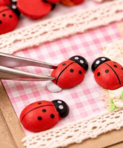 Små træ mariehøns der limes på kort til DIY hobby og dekoration med pincet