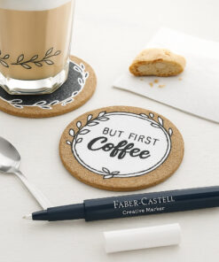 Faber-Castell Creative Marker White as Snow lagt ved kreative korkbordskånere dekoreret med hvid blæk og en latte i baggrunden.