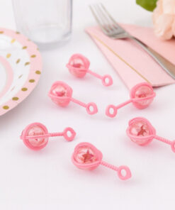 Små lyserøde baby rangler som bordpynt til babyshower og barnedåb på hvidt festbord