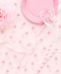 Små lyserøde sutteflasker som bordpynt på pyntet festbord til babyshower