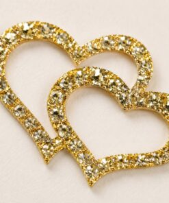 Close-up af selvklæbende rhinsten hjerter i guld med funklende krystaller og dekorativ guldramme til hobby, scrapbooking og kortfremstilling.