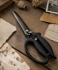 Stemningsbillede af Tim Holtz Recoil Scissors placeret på kreativt hobbybord med papir, scrapbooking-materialer og vintage detaljer.